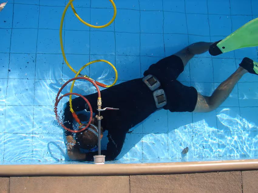 Mergulhador realizando detecção de vazamento em piscina com equipamento especializado